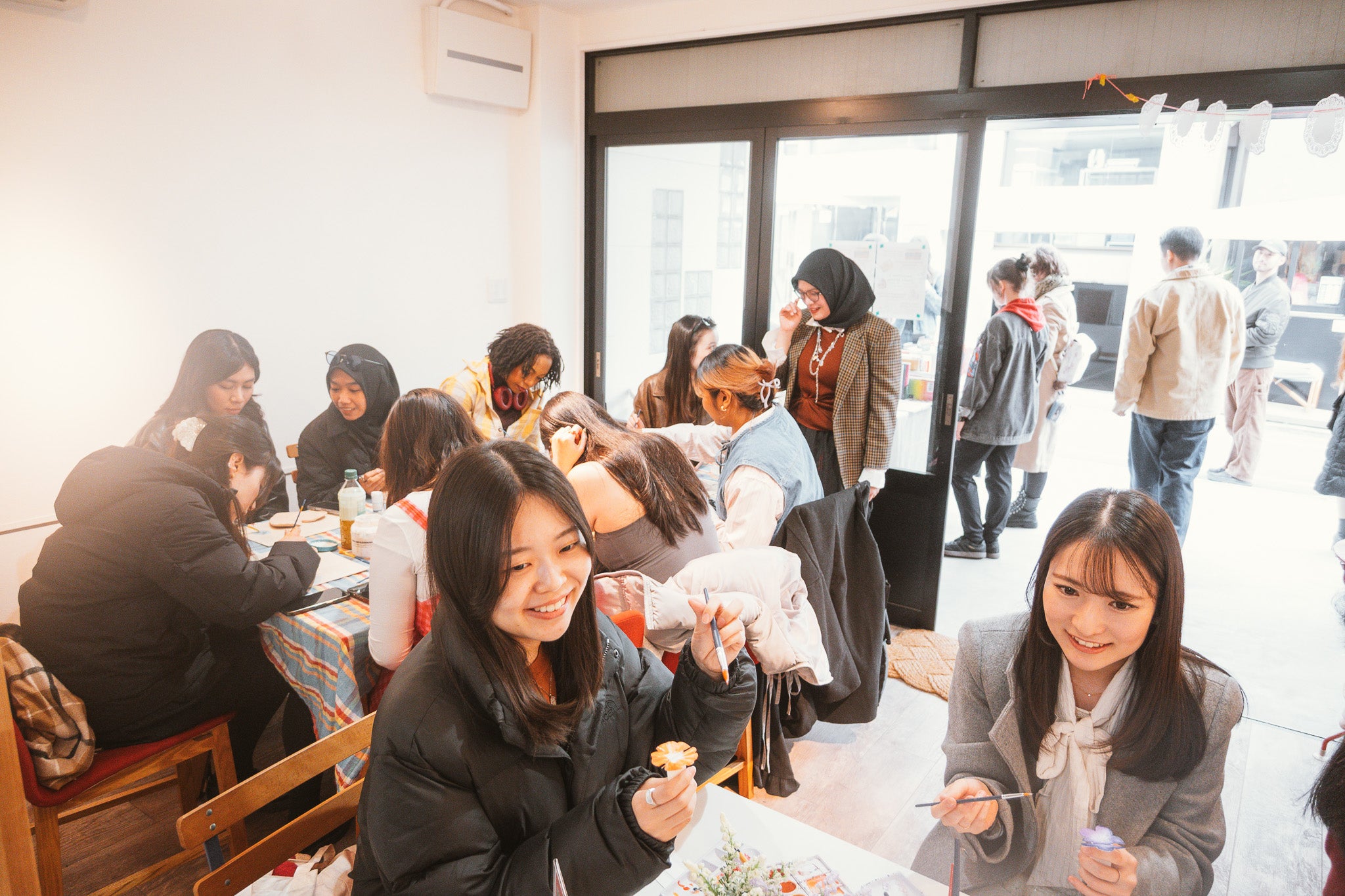 People sitting at tables in a modern indoor setting with large windows.